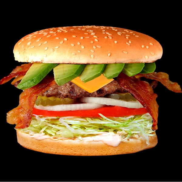 A Jim's Burgers bacon avocado cheeseburger with lettuce, tomato, onion, and pickles on a sesame seed bun.