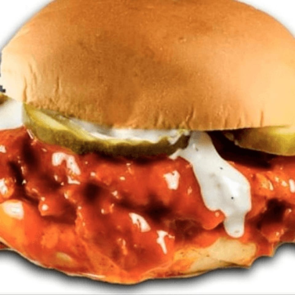 A Jim's Burgers spicy chicken sandwich with pickles and ranch dressing on a bun.