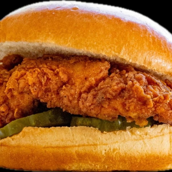 Close-up of a crispy fried chicken sandwich with pickles on a toasted bun.