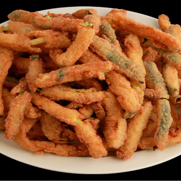 A white plate piled high with golden-brown, crispy fried zucchini sticks from Jim's Burgers.